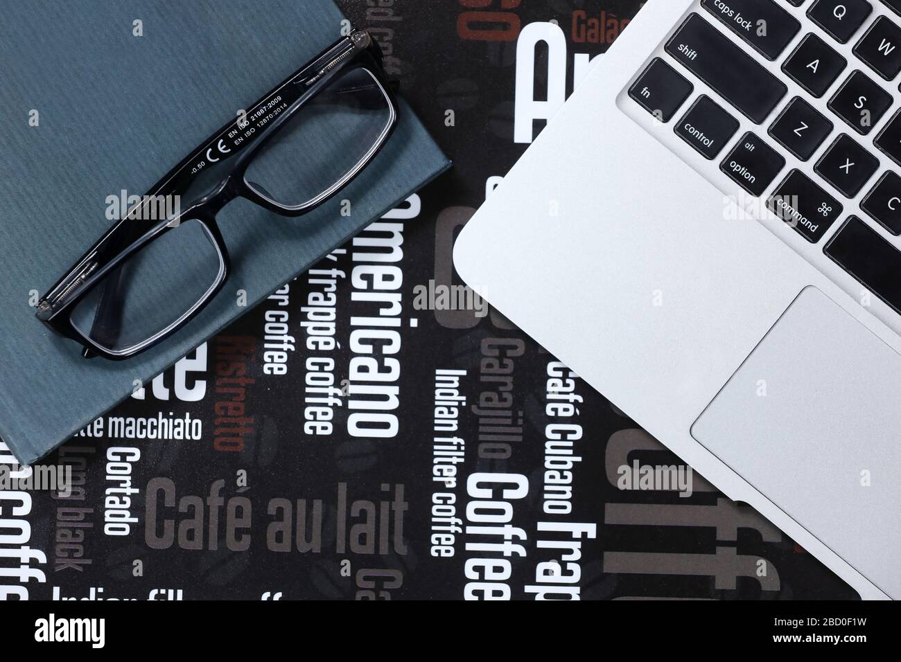 Occhiali neri su un laptop, un libro e un mouse rosso isolati su uno sfondo bianco con testo. Riunione di lavoro. Strategia di marketing. Economia Foto Stock