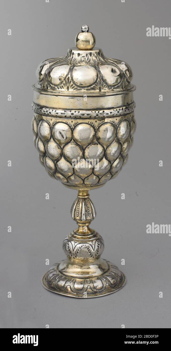 Bicchiere e coperchio in posizione eretta. Ricerca nel modello di ananas Progressrepoussé su tazza(a) e coperchio(b), con fascia di pan-dort al collegamento, sopra uno stelo di lobato e piede. Il finiale della copertura è una sfera dorata in argento fissata alla copertura mediante perno con testa rotonda piccola in argento. Bicchiere e coperchio in posizione eretta Foto Stock