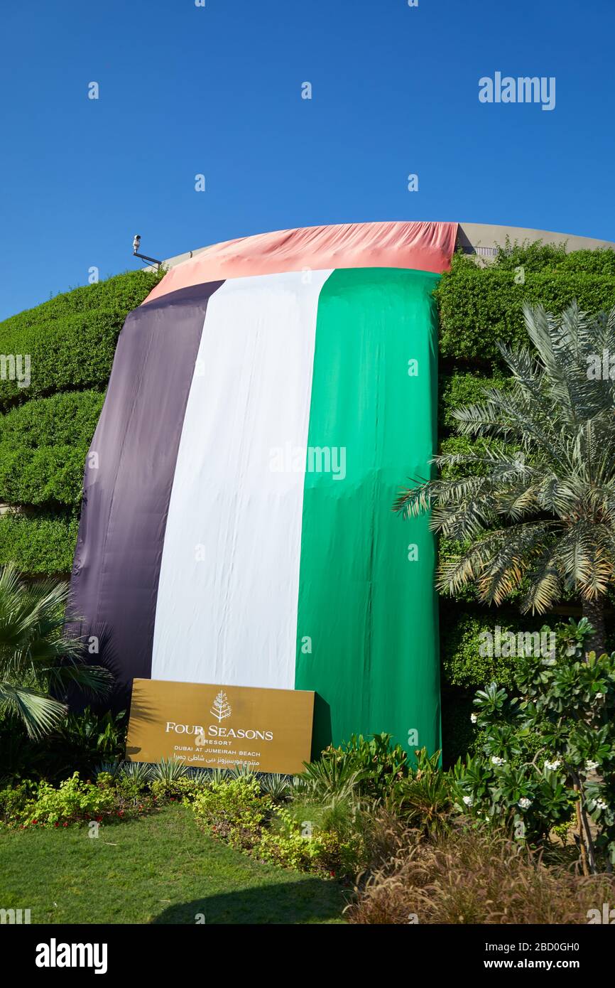 DUBAI, EMIRATI ARABI UNITI - 22 NOVEMBRE 2019: Four Seasons Resort, hotel di lusso con grande bandiera degli Emirati in una giornata di sole, cielo blu chiaro Foto Stock