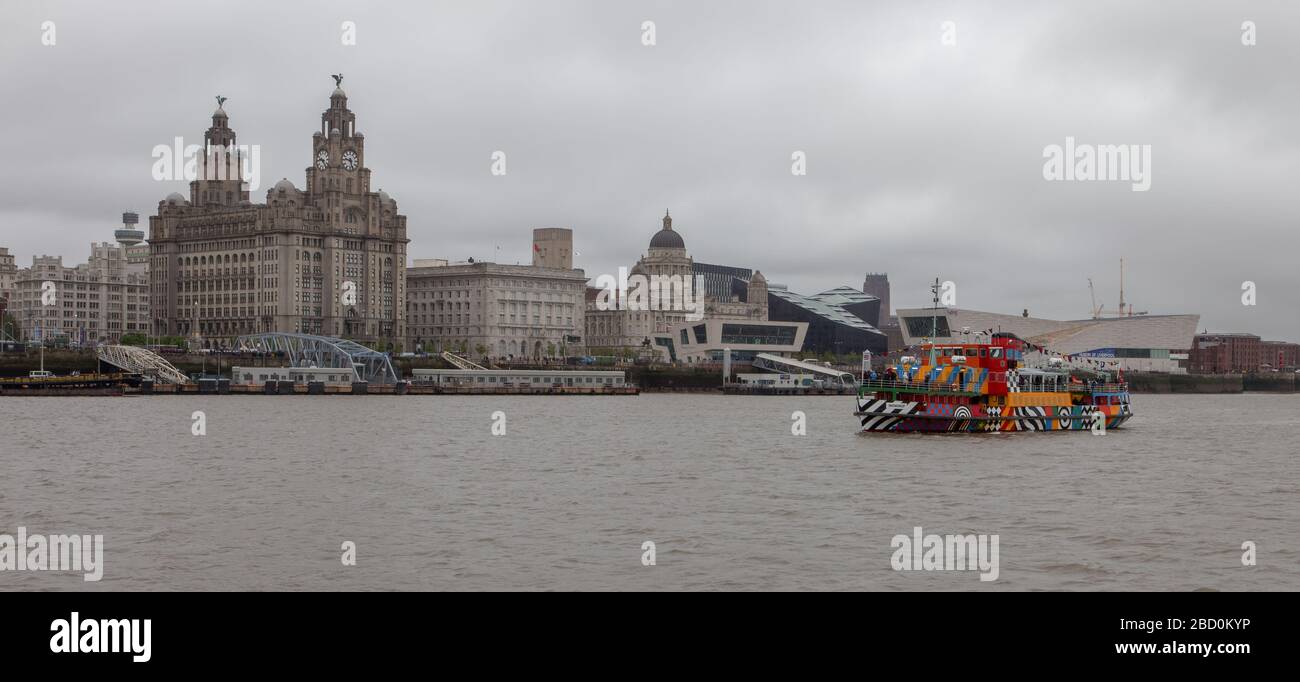 Il Mersey Ferries Snowdrop si avvicina al terminal dei traghetti di Seacombe, con le tre grazie di Liverpool sullo sfondo Foto Stock