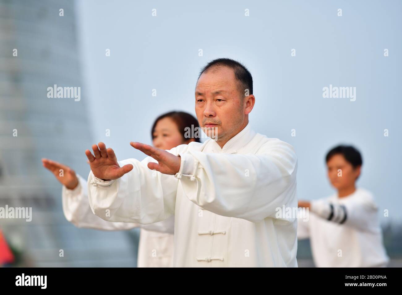 Huzhou, Cina, ottobre 2019; primo piano di uomo parte di un grande gruppo di persone che praticano Tai Chi, stile Yang in prima serata sulla riva del lago Tai Foto Stock