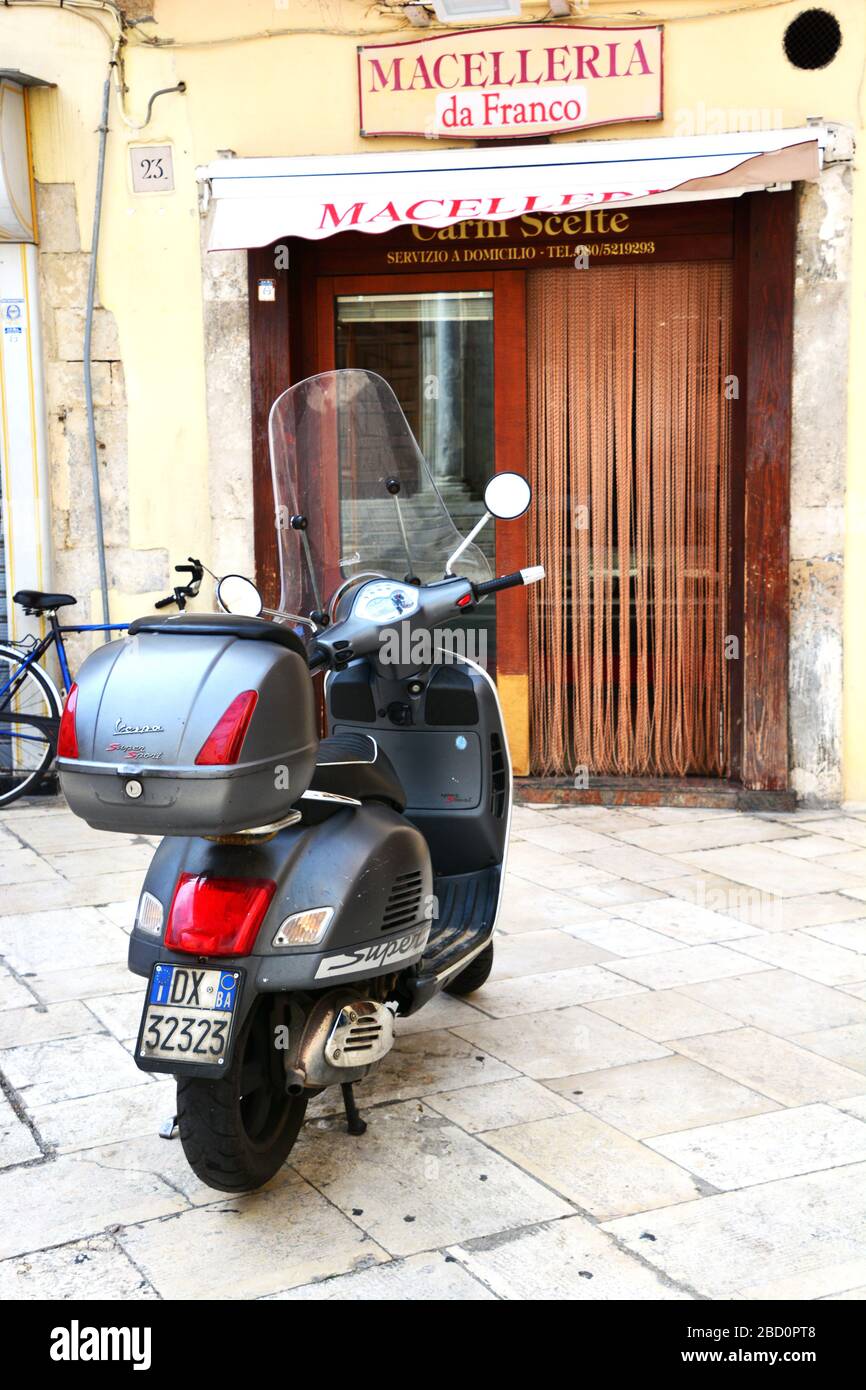 Bari, Italia-Aprile 2019: Primo piano della vespa parcheggiata di fronte al tipico negozio di macelleria italiana Foto Stock