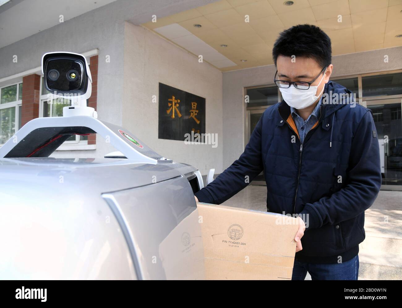 Pechino, Cina. 6 Aprile 2020. Un membro del personale mette le merci in una vettura di consegna senza equipaggio 5G all'Istituto di tecnologia di Pechino, capitale della Cina, 6 aprile 2020. All'Istituto di tecnologia di Pechino è stata messa in uso un'auto da consegna senza equipaggio da 5 G, in grado di misurare la temperatura delle persone che entrano nel campus, riconoscere le informazioni facciali e anche di effettuare consegne senza contatto. Credit: Ren Chao/Xinhua/Alamy Live News Foto Stock
