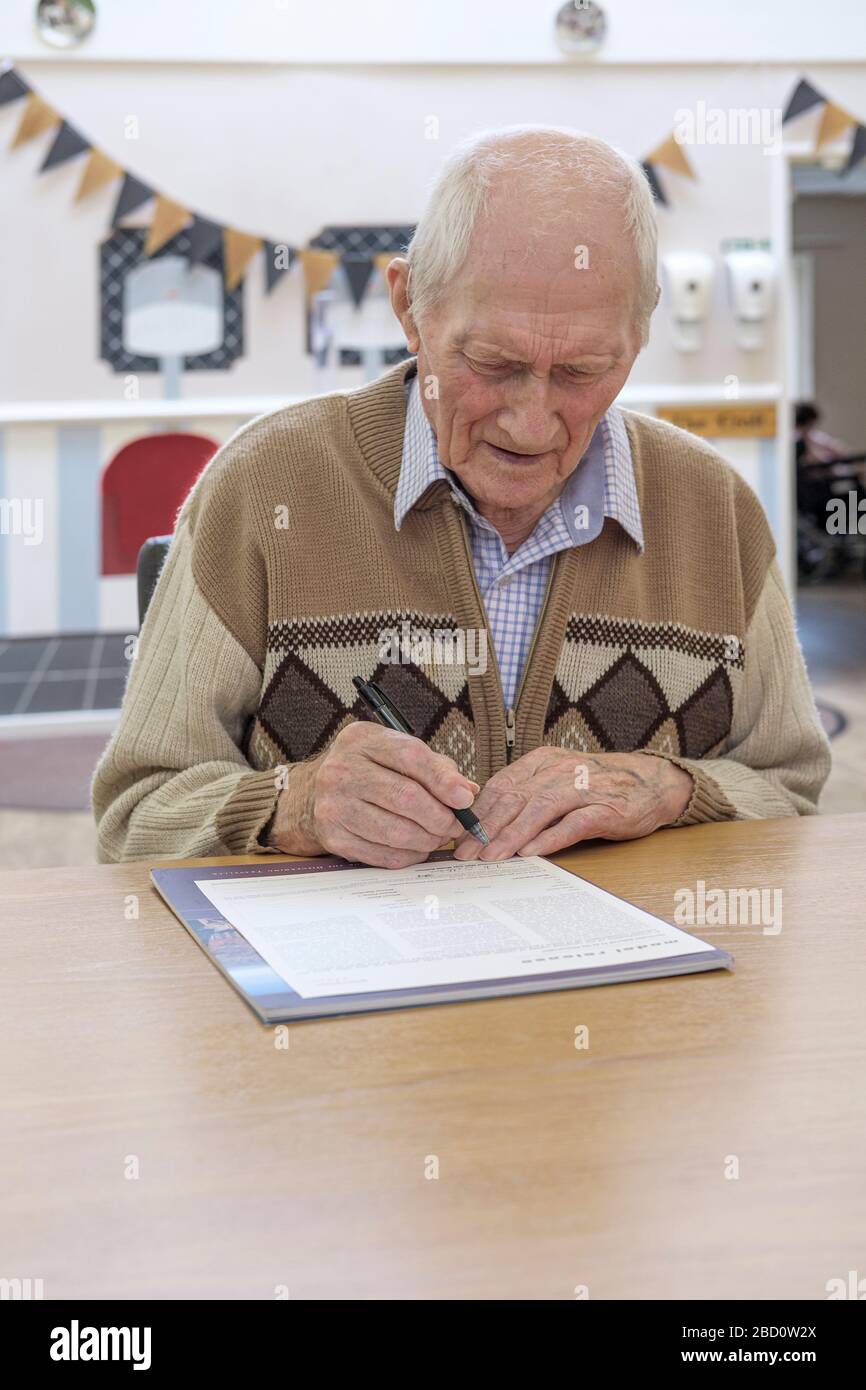 Uomo di 97 anni che firma il modello di rilascio, documento legale Foto Stock