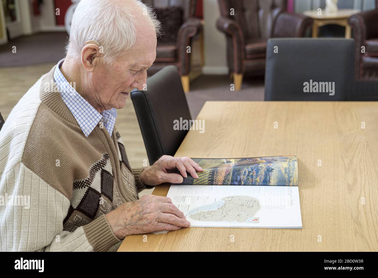 uomo di 97 anni che legge la brochure di viaggio Foto Stock
