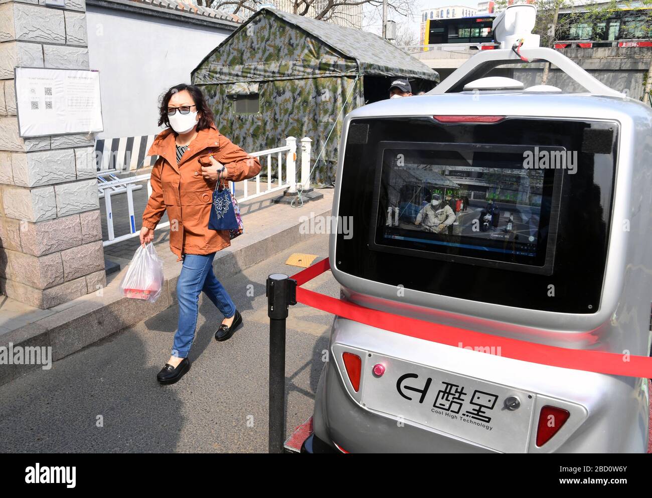 Pechino, Cina. 6 Aprile 2020. Una vettura di consegna senza equipaggio 5G misura la temperatura di una donna che cammina nell'Istituto di tecnologia di Pechino, capitale della Cina, il 6 aprile 2020. All'Istituto di tecnologia di Pechino è stata messa in uso un'auto da consegna senza equipaggio da 5 G, in grado di misurare la temperatura delle persone che entrano nel campus, riconoscere le informazioni facciali e anche di effettuare consegne senza contatto. Credit: Ren Chao/Xinhua/Alamy Live News Foto Stock