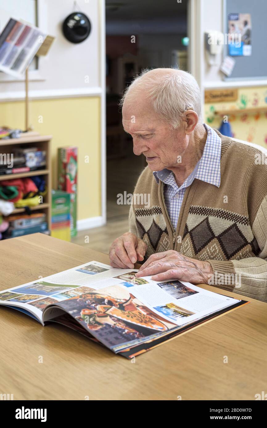 uomo di 97 anni che legge la brochure di viaggio Foto Stock