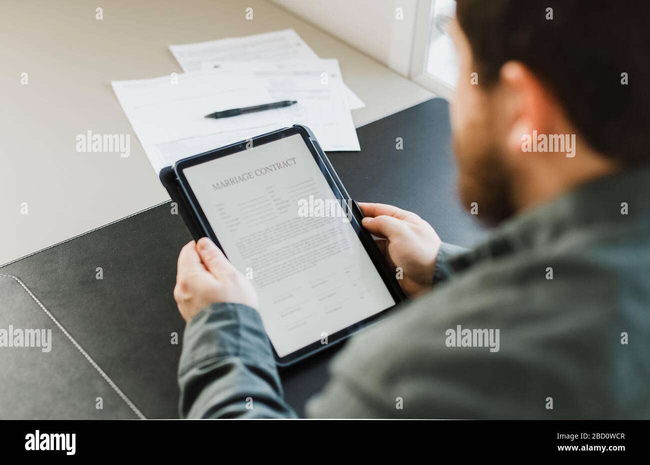 Uomo che legge il contratto di matrimonio su tablet in ufficio. Foto Stock