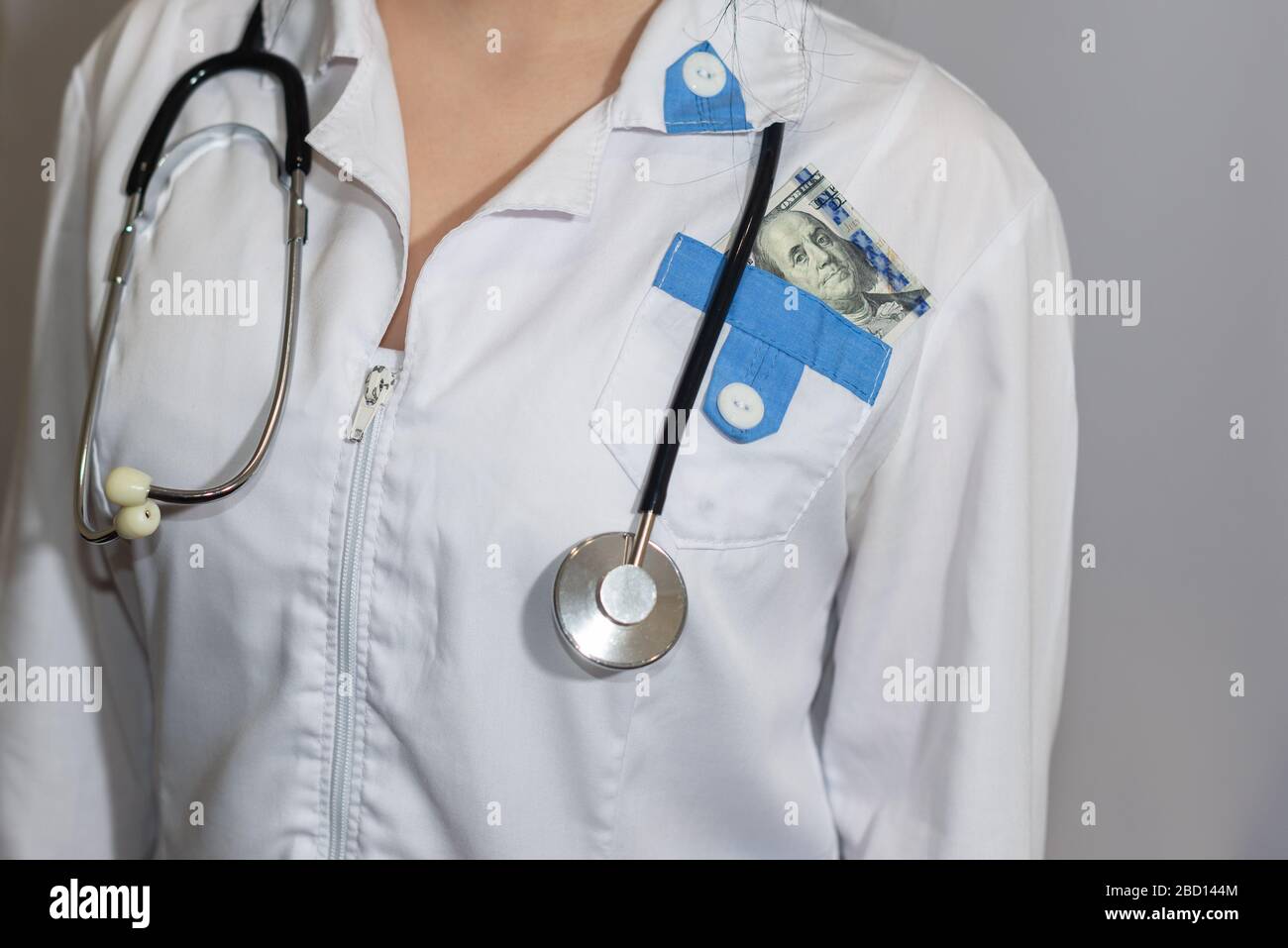 Tangente. Cento dollari di fattura in tasca di un medico o paramedico. Corruzione in medicina, farmaceutica. Il concetto di medicina pagata. Foto Stock