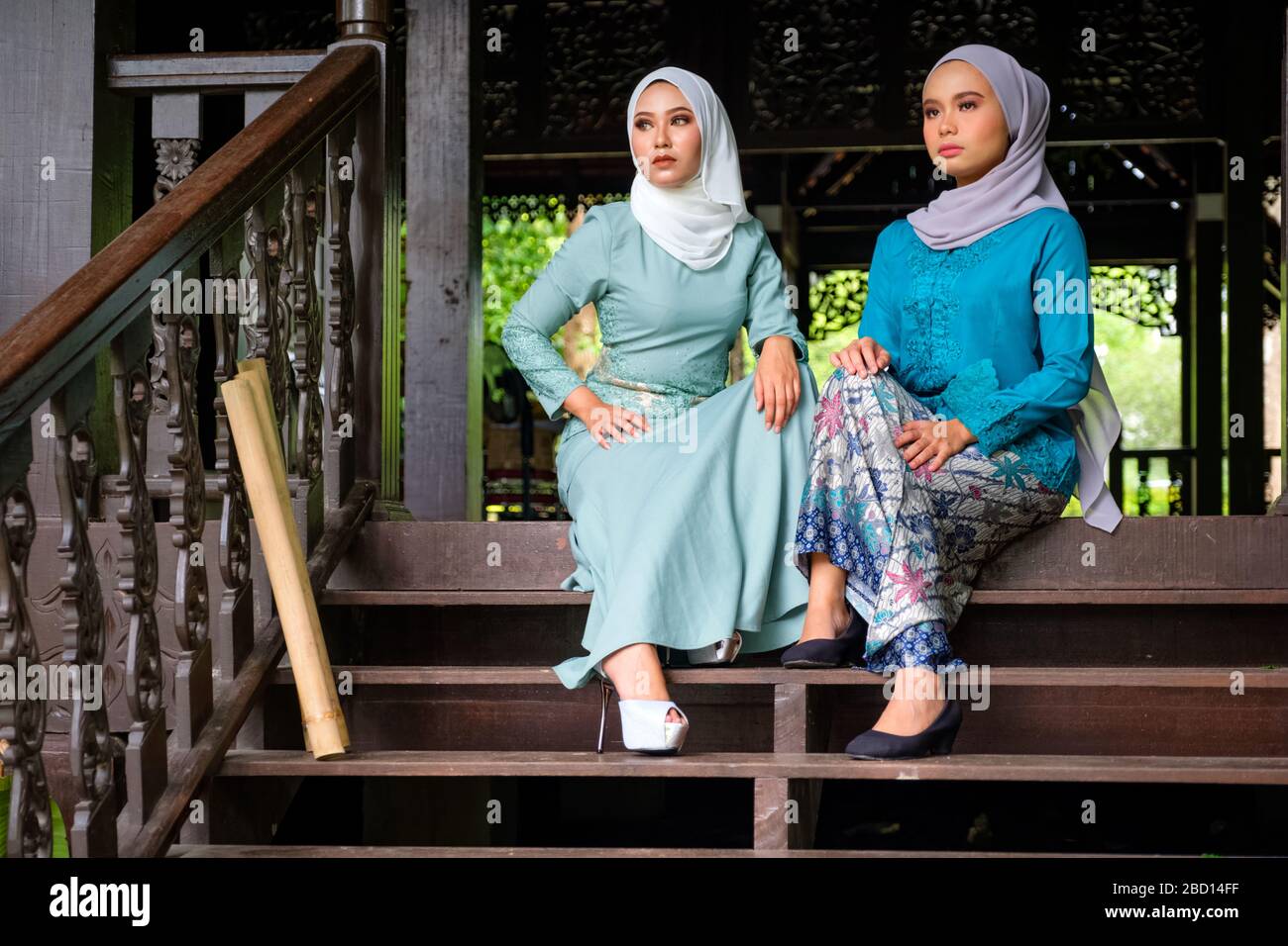 Ritratto di donne malesi musulmane che indossano hijab e costume tradizionale durante le celebrazioni Aidilfitri sulla terrazza della casa tradizionale in legno. Hari R Foto Stock