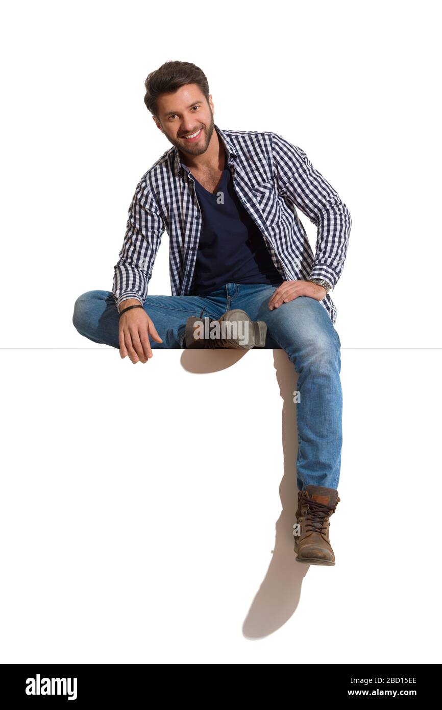 Un giovane uomo rilassato con stivali jeans e camicia sbottonata