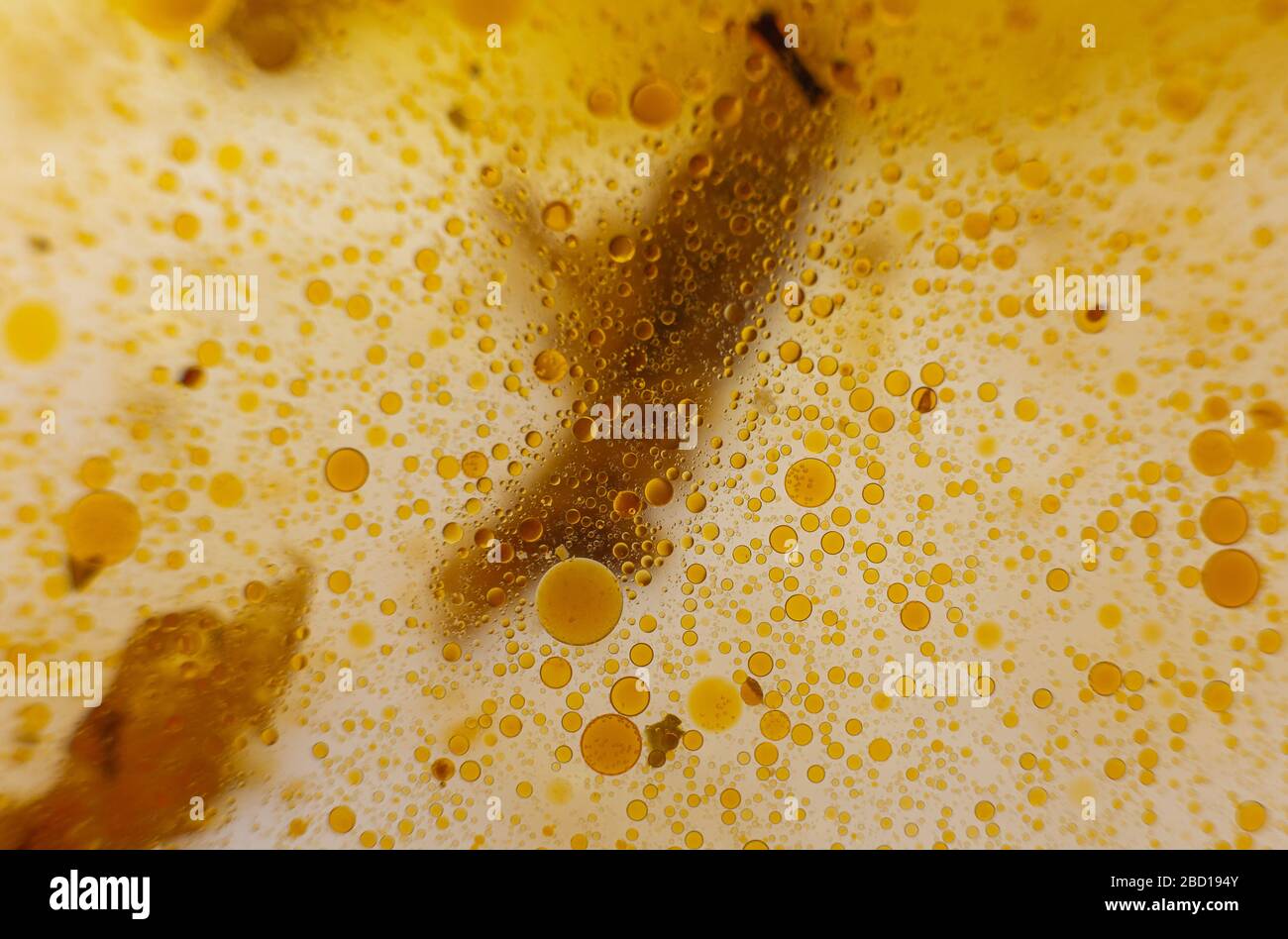 Macchie di olio giallo sull'acqua. Olive in una padella. Macro immagini di macchie grasse. Cupcake gialli. Liquido Geta. Fondazione velluto. Foto Stock