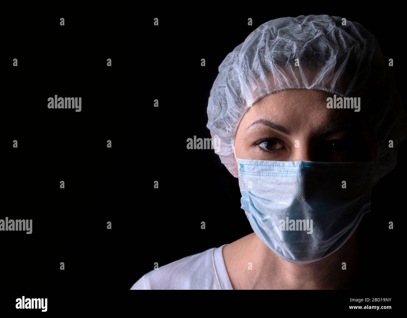 Ritratto di medico donna che indossa maschera protettiva su sfondo nero Foto Stock