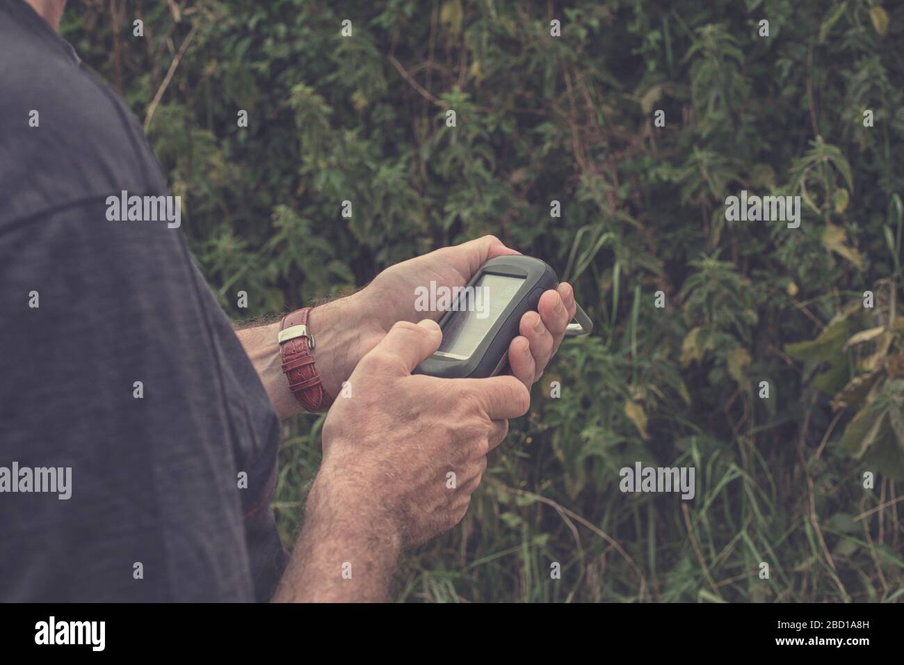 Uomo in possesso di un ricevitore GPS in mano. Dispositivi palmari GPS sono utilizzati prevalentemente per l'outdoor industria del tempo libero per escursioni e passeggiate. Foto Stock