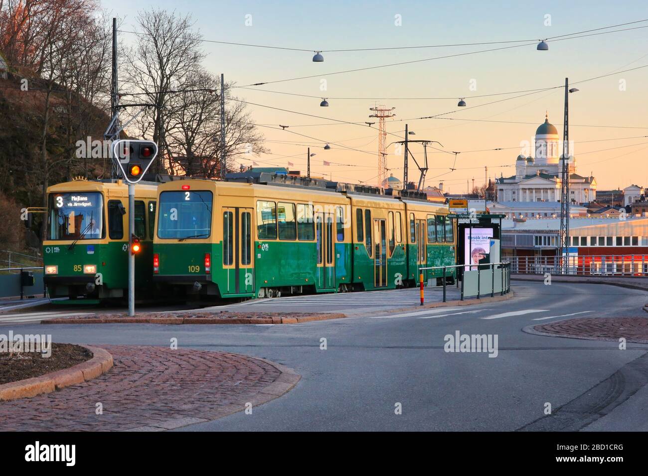 Due tram HSL, 2 e 3 all'Olympia Terminal fermata del tram in una tranquilla mattina all'alba, sullo sfondo della cattedrale di Helsinki. Helsinki, Finlandia. Apr 4, 2020. Foto Stock