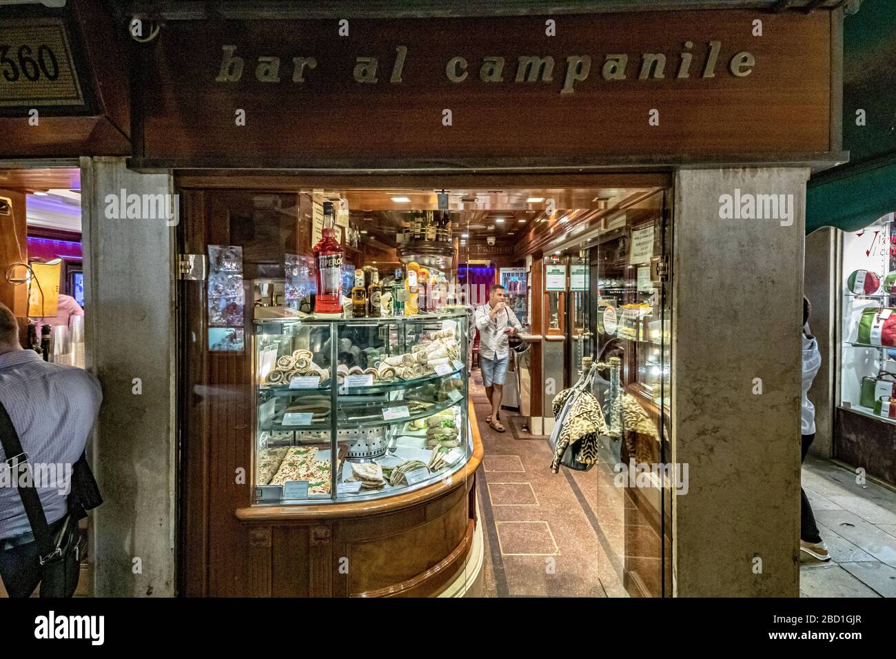 Un uomo gode di un bicchiere di vino e di alcuni cicchetti all'interno del Bar al Campanile in Calle larga S. Marco , Venezia, Italia Foto Stock