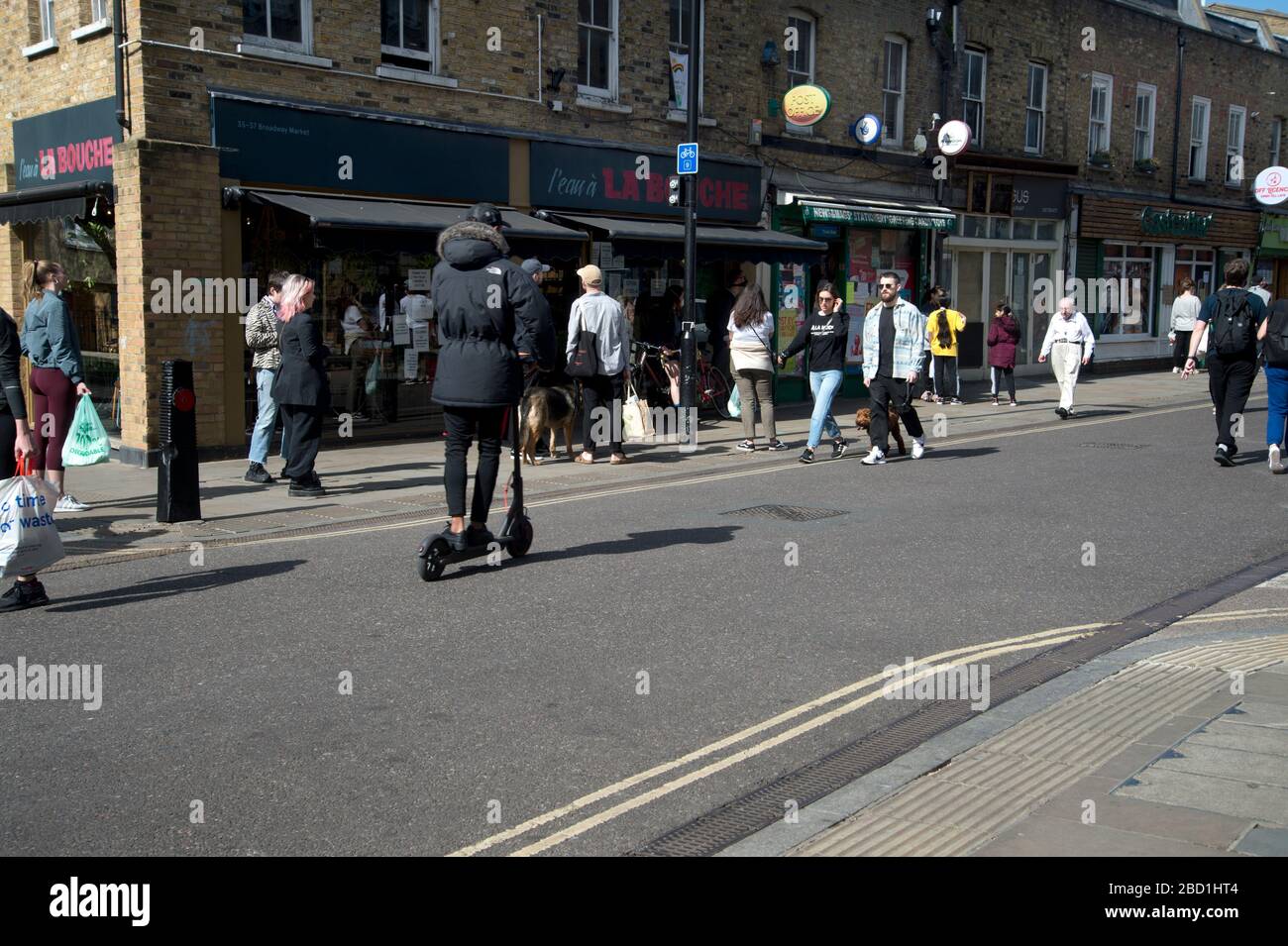 Londra, Hackney. Coronavirus pandemico. Mercato di Broadway. Non c'è traffico, ma c'è una coda che aspetta fuori la Bouche. Foto Stock