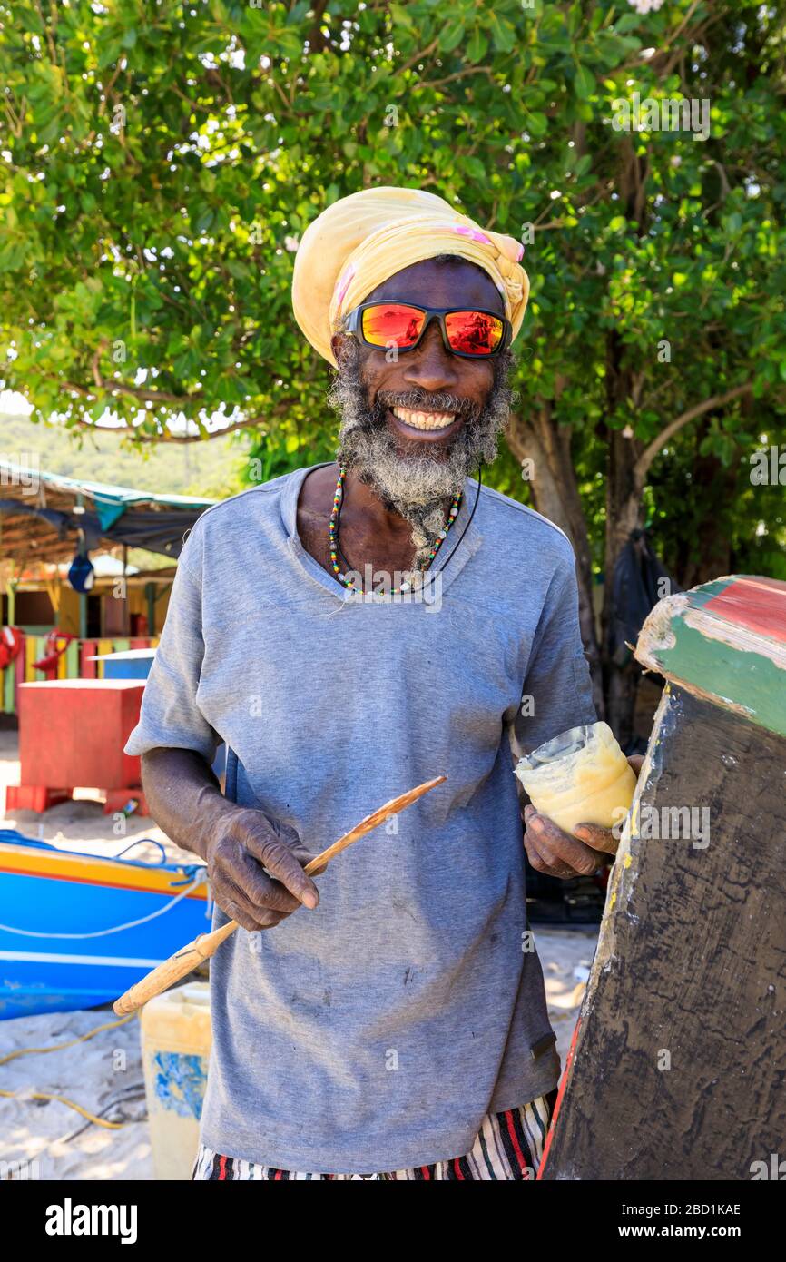 Grinning uomo ripara barca, colorato Saltwhistle Bay, Mayreau, Grenadine, St. Vincent e Grenadine, Windward Islands, Caraibi Foto Stock