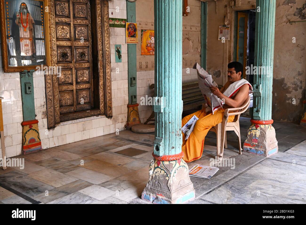 Prete indù che legge il quotidiano in un vecchio tempio di backstreet nei palls (vicoli) della vecchia Ahmedabad, Gujarat, India, Asia Foto Stock