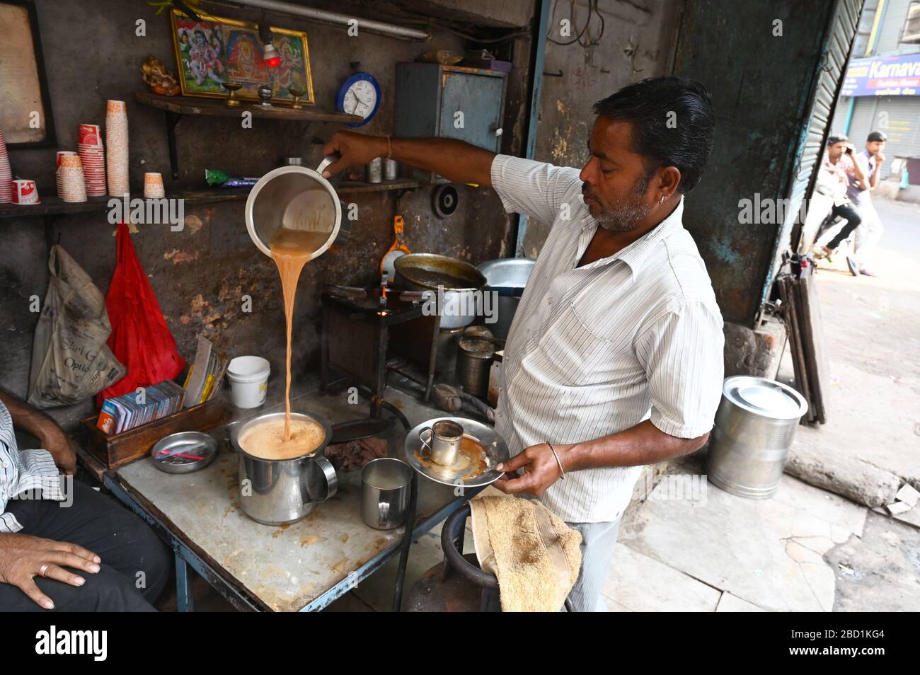 Chaiwallah affollato che versa il tè ad una stalla del chai nei palls (vicoli) della vecchia Ahmedabad, Gujarat, India, Asia Foto Stock