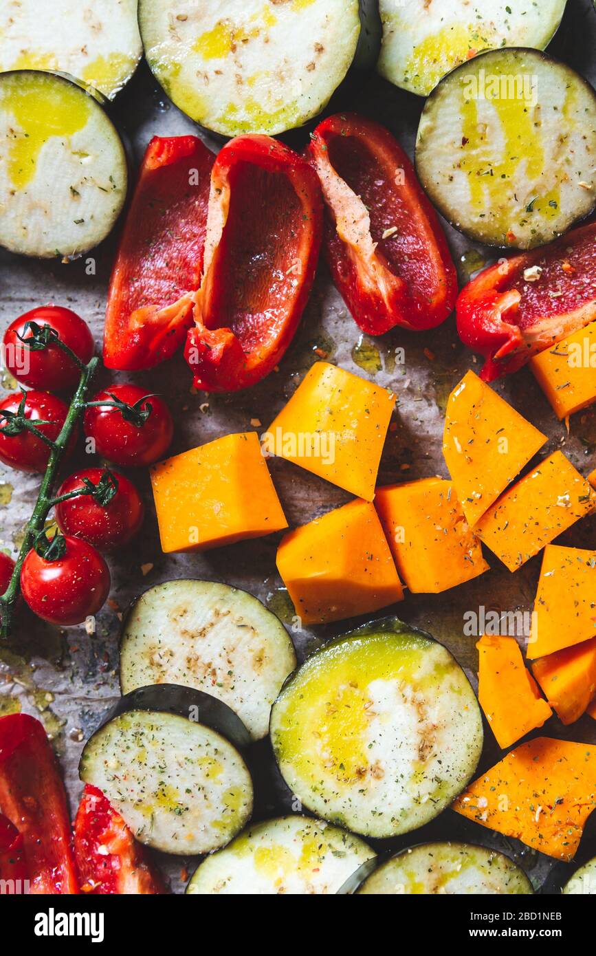 Cena Detox salutare con verdure diverse, come melanzane, pepe rosso, pomodori ciliegini, zucca alle butternut. Fette di verdure crude preparate per la torrefazione, semplice pasto di famiglia Foto Stock