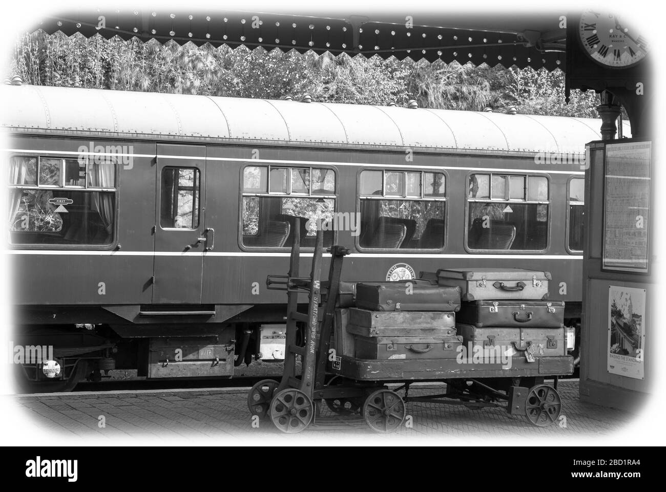 Vista mono bianco e nero, piattaforma della stazione ferroviaria vintage di Bewdley, Severn Valley Heritage Railway, Regno Unito. Bagagli vintage, valigie sul carrello per bagagli. Foto Stock