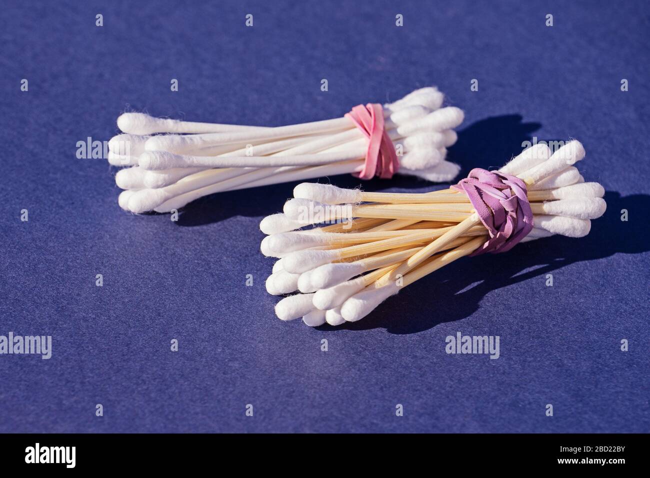 Bastoncini di cotone di bambù contro bastoncini di cotone di plastica su sfondo viola. Spazio di copia, concetto zero sprechi, eco-friendly Foto Stock