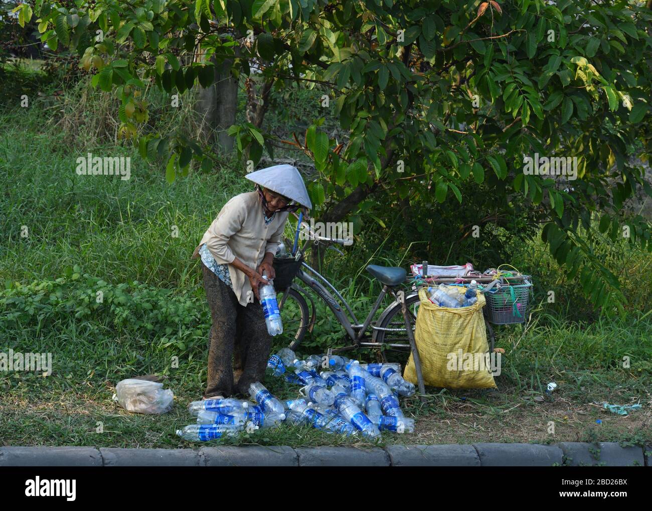 Una signora senior raccoglie bottiglie di plastica vuote per le strade di da Nang, Vietnam, per il riciclaggio per fare qualche spesa. Foto Stock
