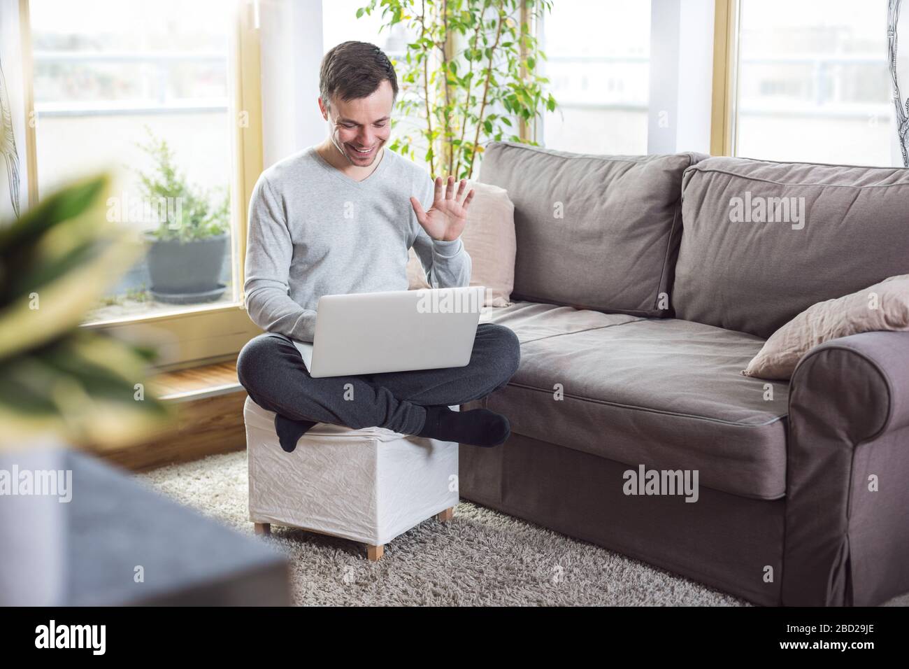 Uomo a casa che svegli sullo schermo del notebook Foto Stock