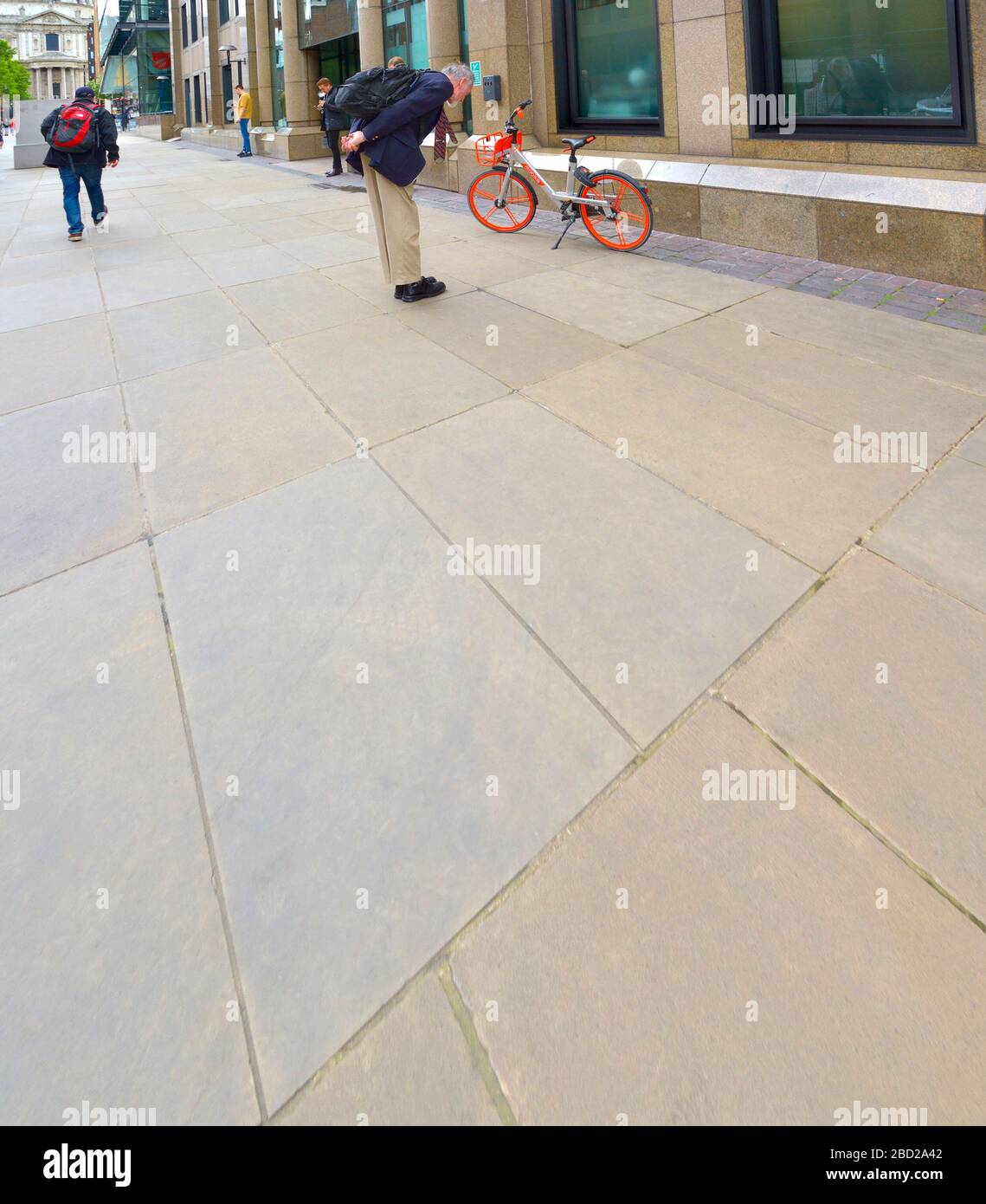 Londra, Inghilterra, Regno Unito. Un uomo che guarda una bici a noleggio "mobike" a Peter's Hill, vicino a St. Pauls Foto Stock