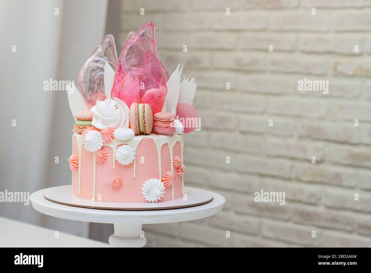 Torta rosa moderna con decorazioni al cioccolato, caramello, macaron francesi, meringhe e carta per waffle. Foto Stock