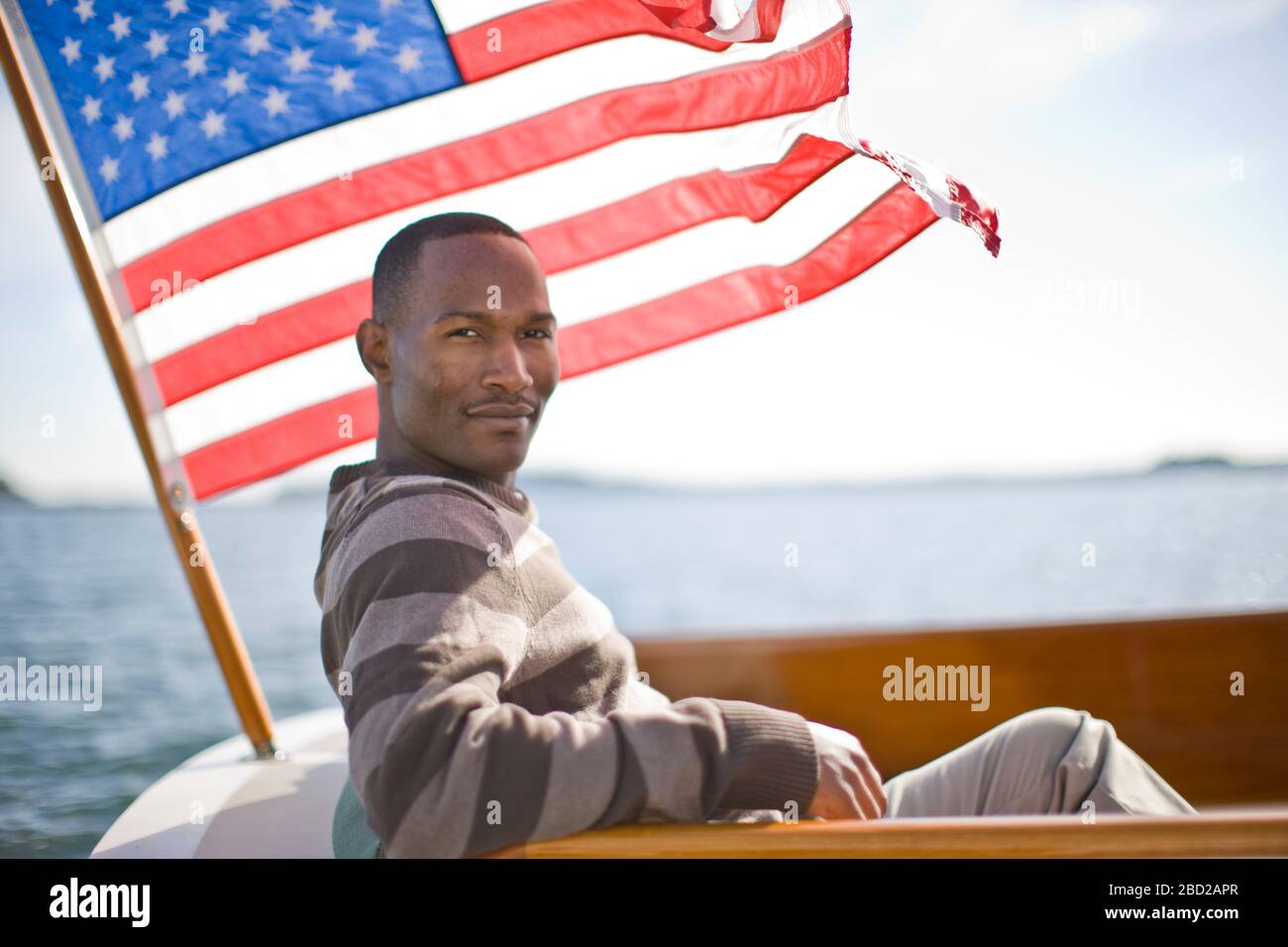 Giovane uomo in barca accanto alla bandiera americana Foto Stock