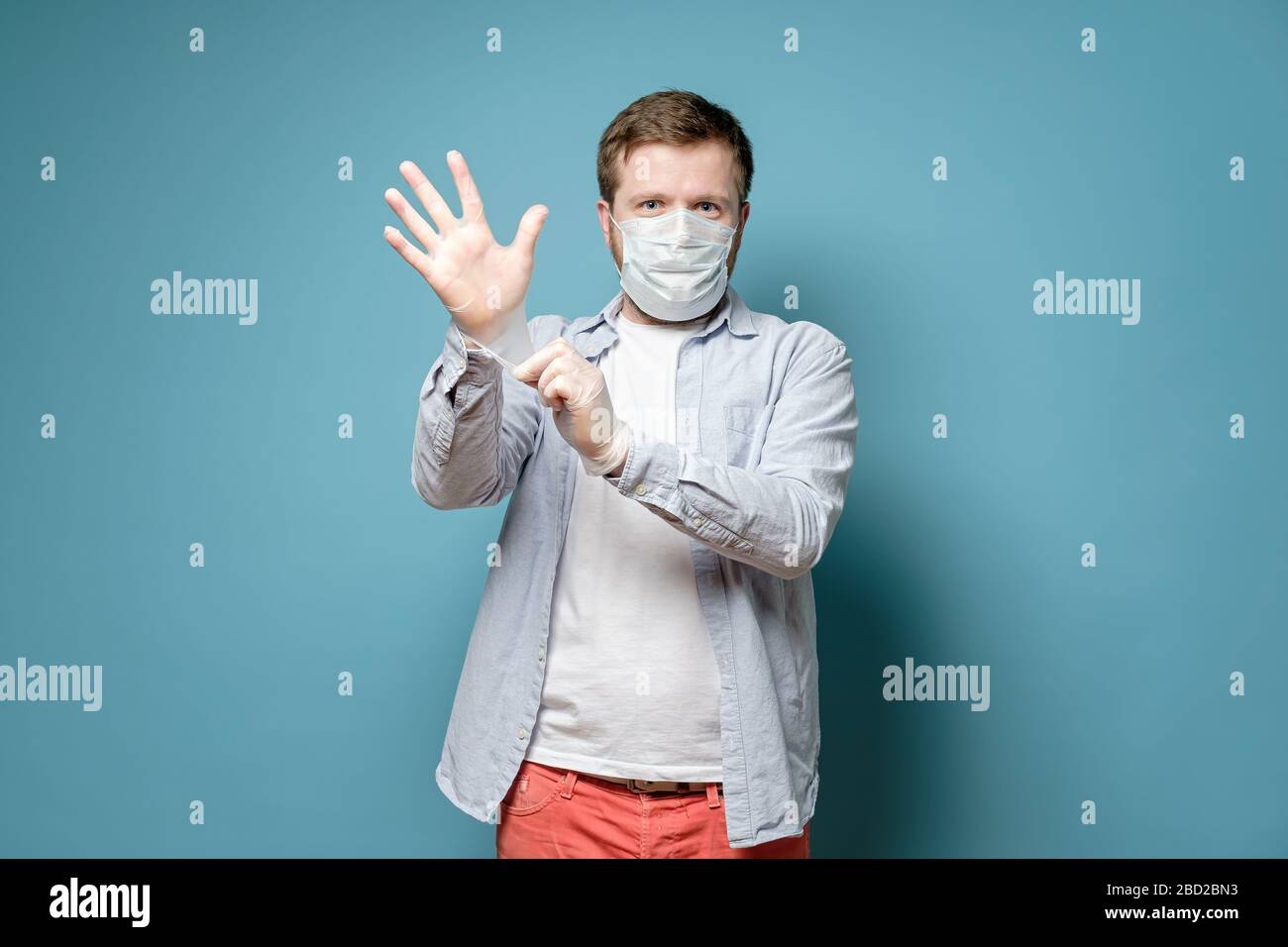 L'uomo in una maschera medica indossa guanti in lattice, è sicuro di essere in grado di proteggersi da un virus. Concetto di salute. Foto Stock