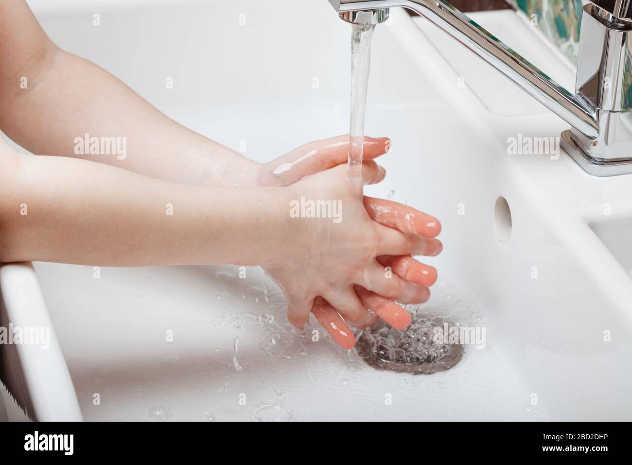 Il bambino rinse le mani lavate nel bagno di casa. Foto Stock