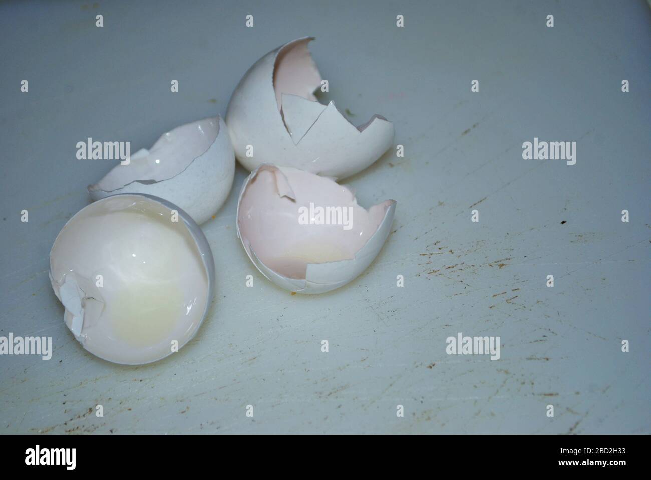 Primo piano di due gusci d'uovo incrinati su un tagliere ben usato Foto Stock