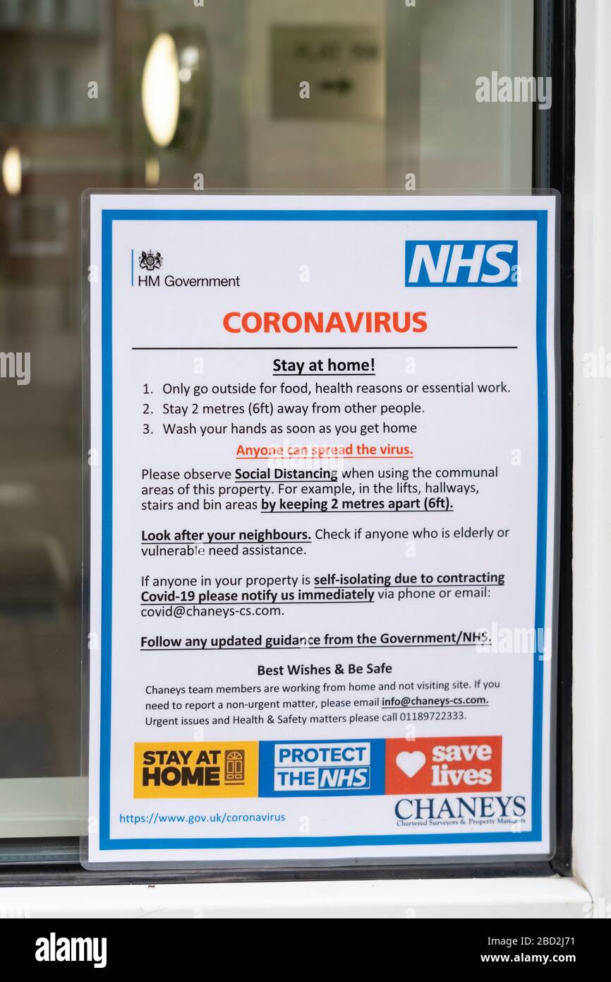 Un avviso ufficiale del governo vicino ad una porta comunale per gli appartamenti che consigliano al pubblico di rimanere a casa durante la pandemia di Coronavirus, 2020 aprile, Regno Unito Foto Stock