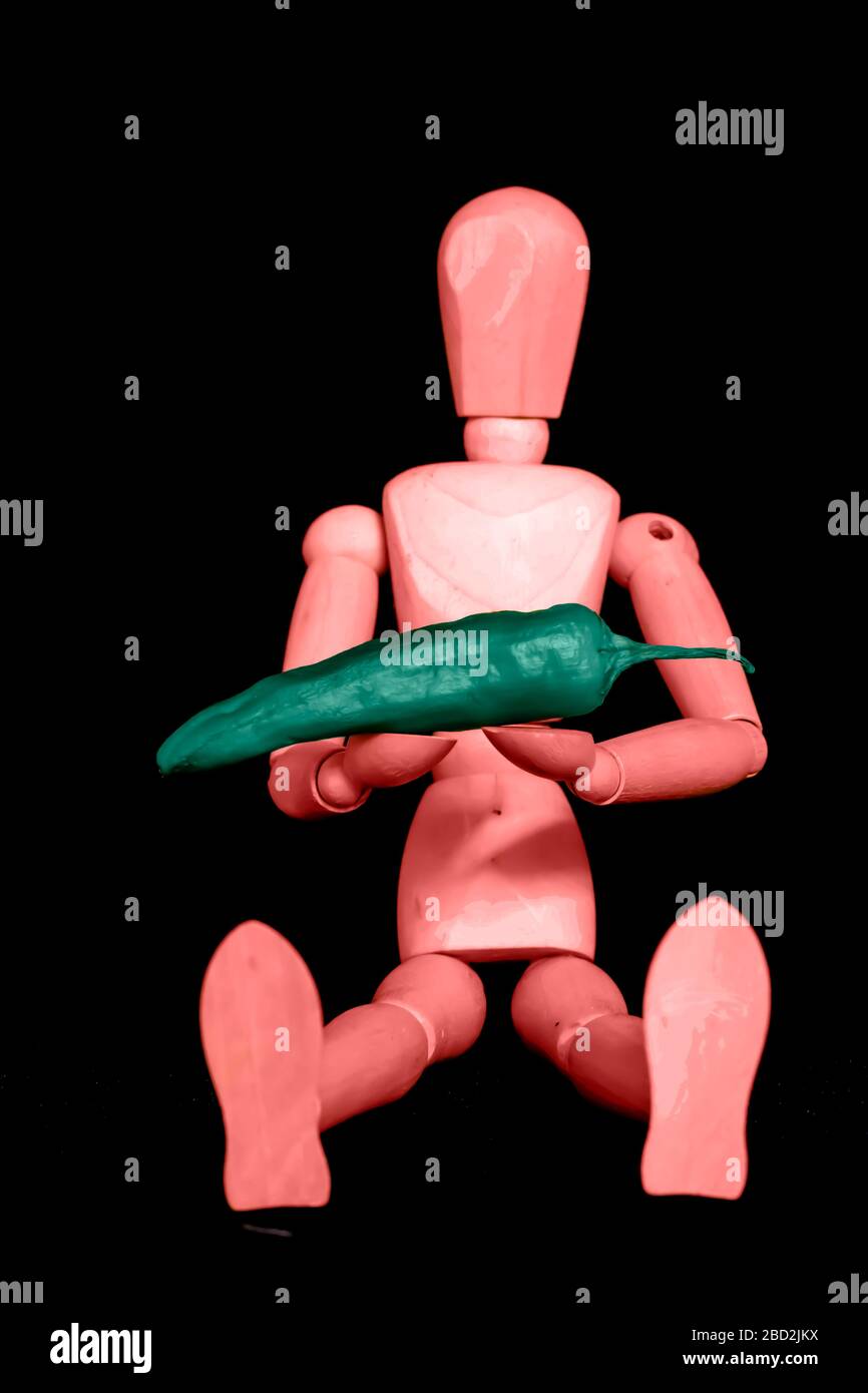 Manichino di legno seduto con un pepe tra le braccia colorato di rosso lava e aqua menthe toni e isolato su uno sfondo nero. Foto Stock