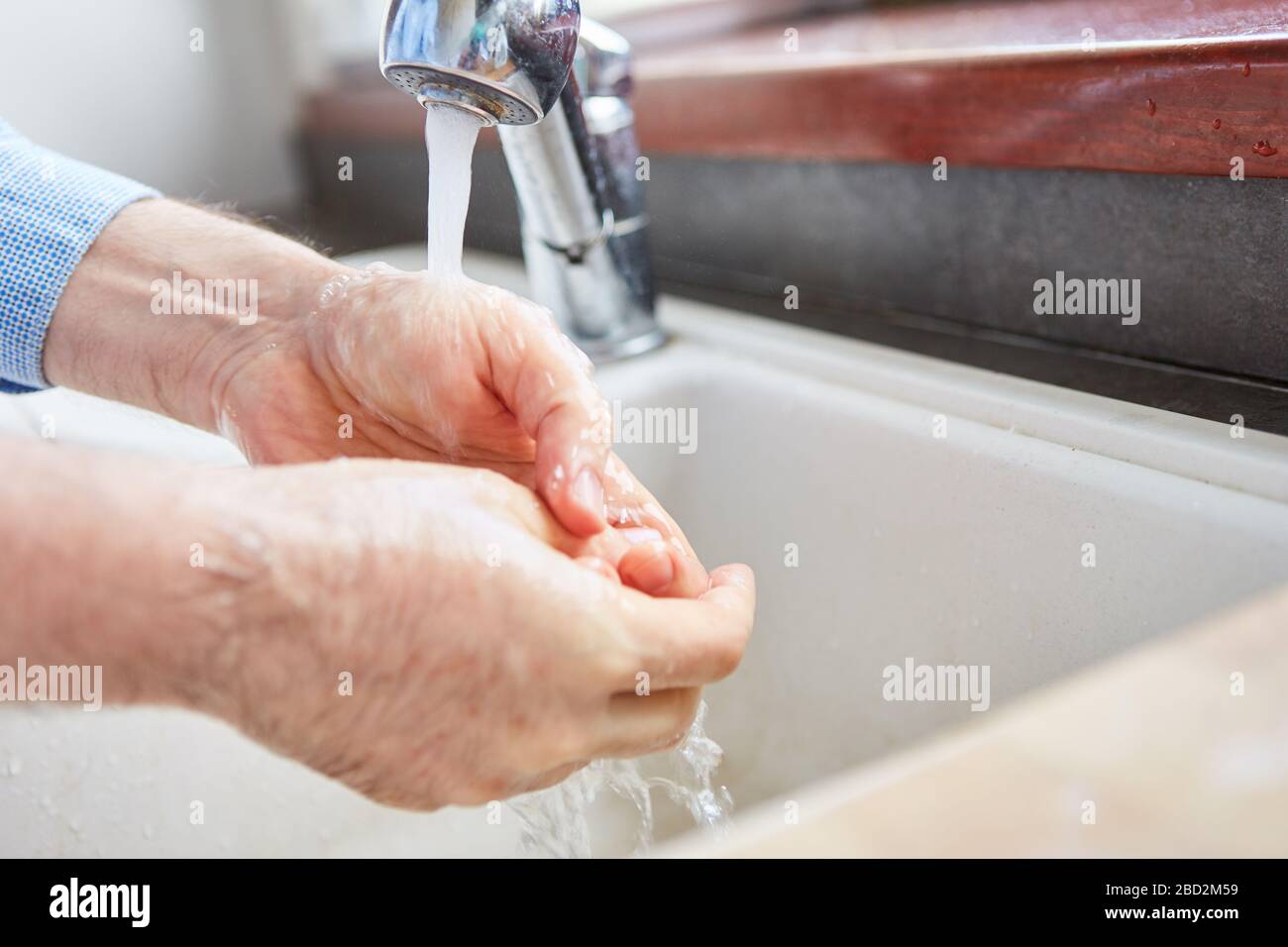 Senior lavando le mani con sapone e acqua a lavello nella crisi del coronavirus Foto Stock
