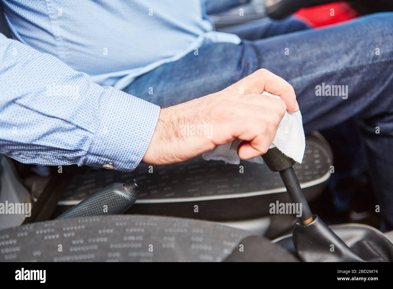Disinfettare gli automobilisti utilizzando la leva del cambio della vettura in caso di pandemia di coronavirus Covid-19 Foto Stock
