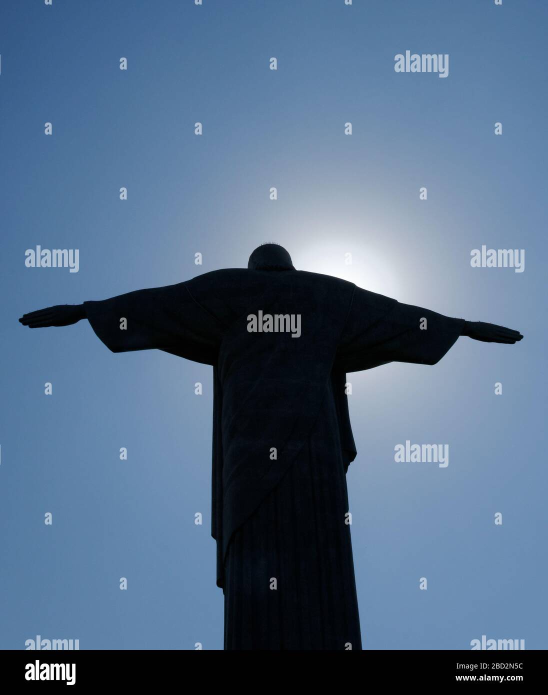 Le braccia estese della statua di Gesù Cristo Redentore sul monte Corcovado, Rio De Janeiro contro il sole che crea una silhouette. Foto Stock