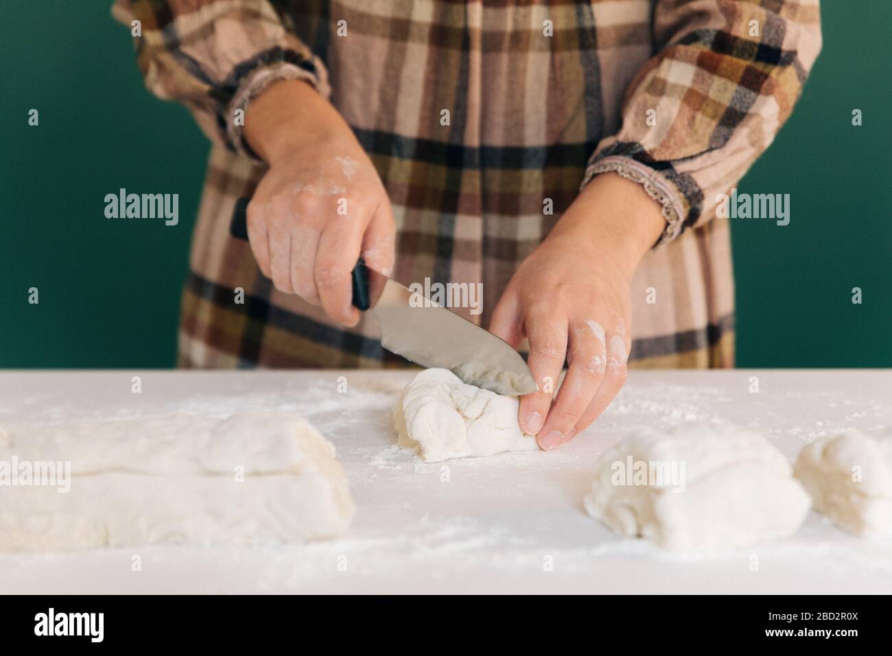 Donna taglia pezzi di pasta per preparare il suo pane fatto a mano, cucina fatta in casa. Foto Stock