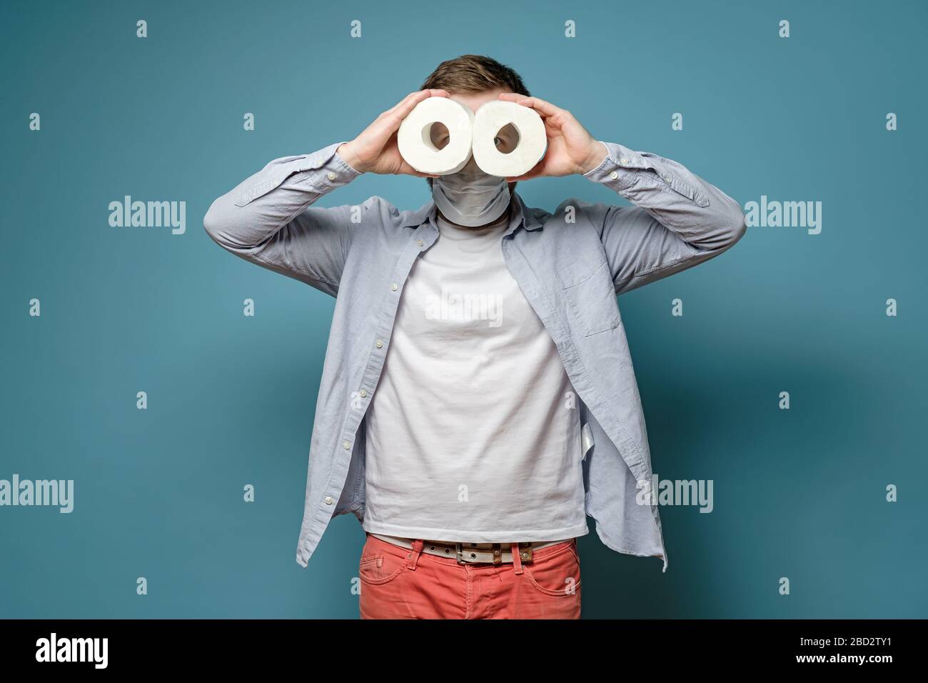 L'uomo in una maschera medica guarda in due rotoli di carta igienica come  il binocolo. Concetto di carenza di merci durante un focolaio di virus Foto  stock - Alamy