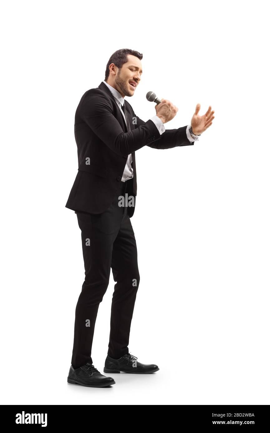 Scatto a tutta lunghezza di un uomo in tuta nera che canta su un microfono isolato su sfondo bianco Foto Stock