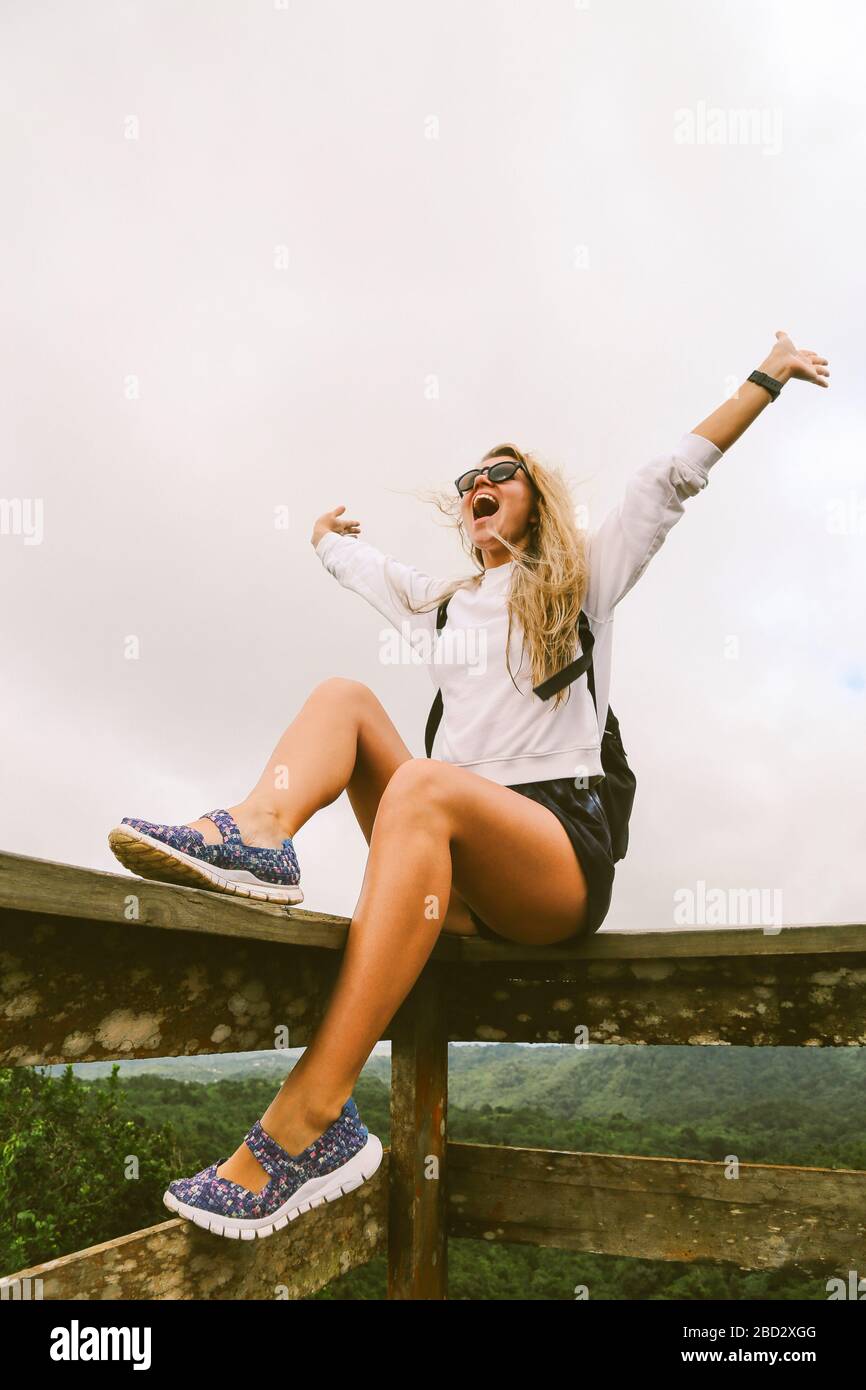 Girl Traveler sulla cima di montagna godendo di vista aerea mani sollevate sopra le nuvole. Viaggiare Lifestyle concetto avventura felicità libertà emozioni Foto Stock