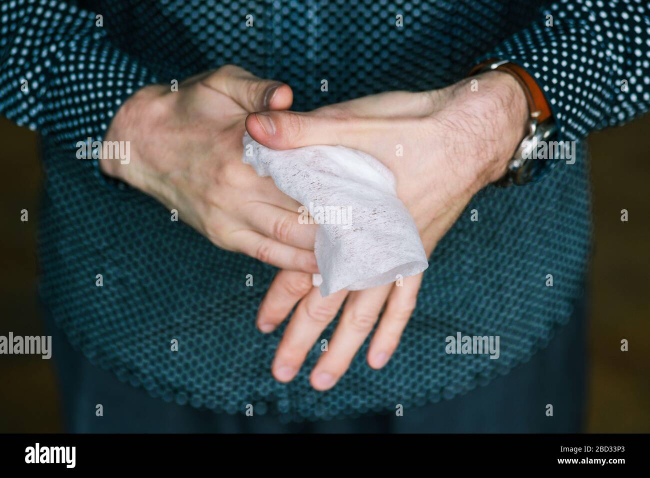 L'uomo pulisce le mani con un panno morbido bianco. Disinfezione contro virus e batteri a casa o in ufficio Foto Stock