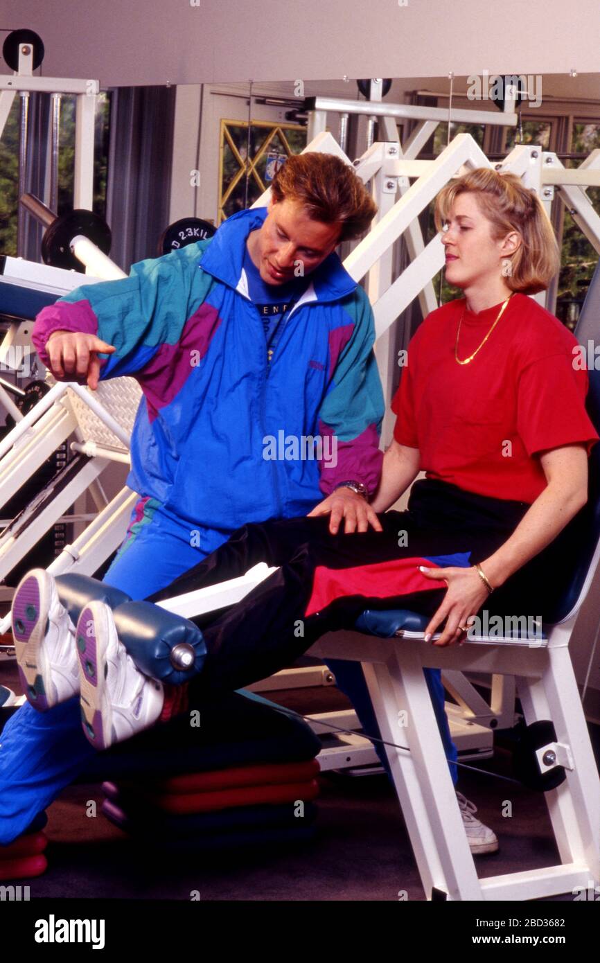 Il personal trainer lavora con il cliente nel centro fitness facendo lift di sinistra sulle attrezzature per esercizi Foto Stock