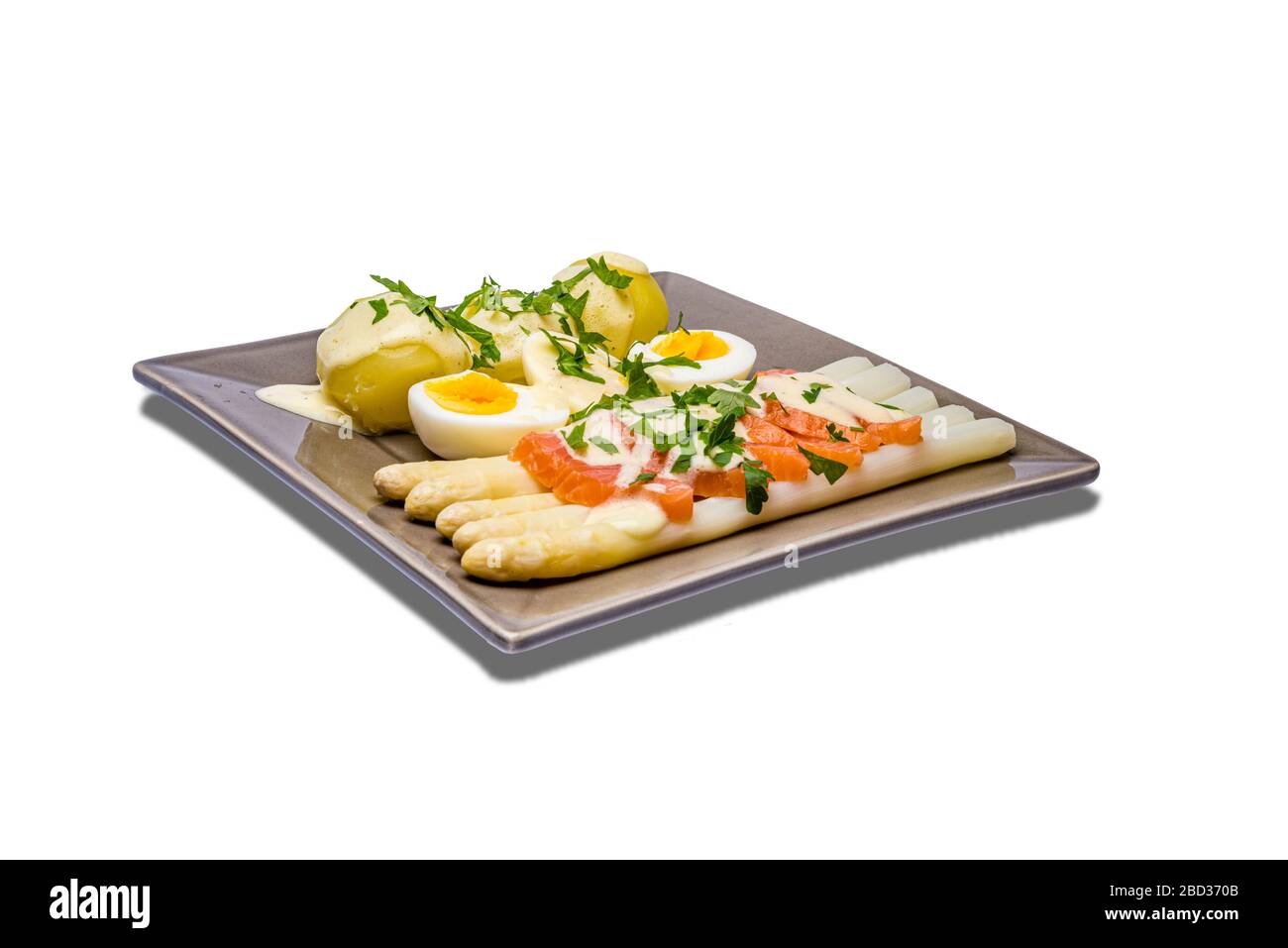 Deliziosi asparagi bianchi di stagione con salsa cremosa di Hollandaise, patate bollite e salmone affumicato a fette su un piatto rustico con limone, wi bianco Foto Stock