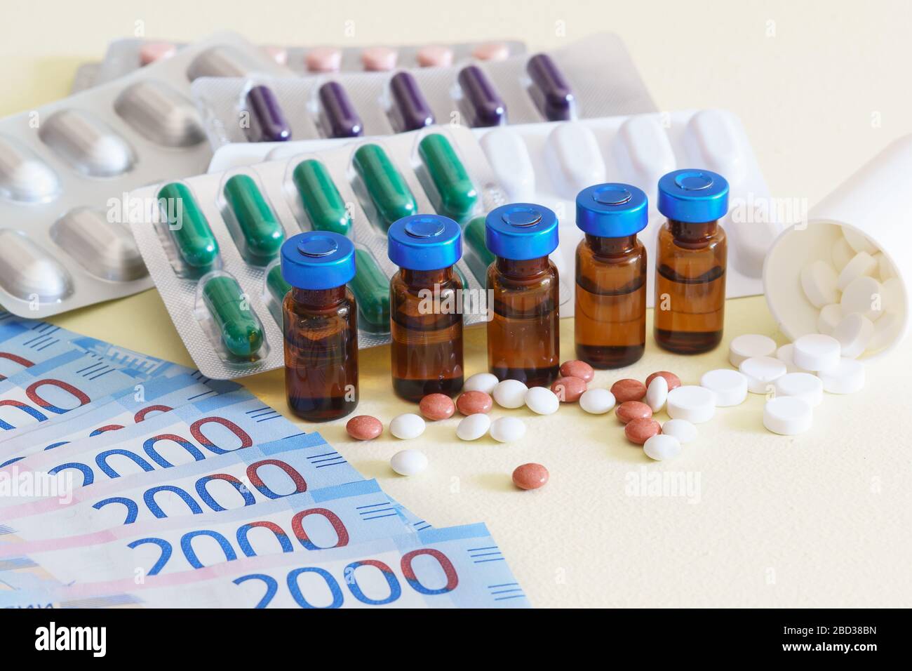 Fiale di farmaci iniettabili, pillole sparse, e denaro russo su una tavola gialla. Trattamento costoso. Messa a fuoco selettiva Foto Stock