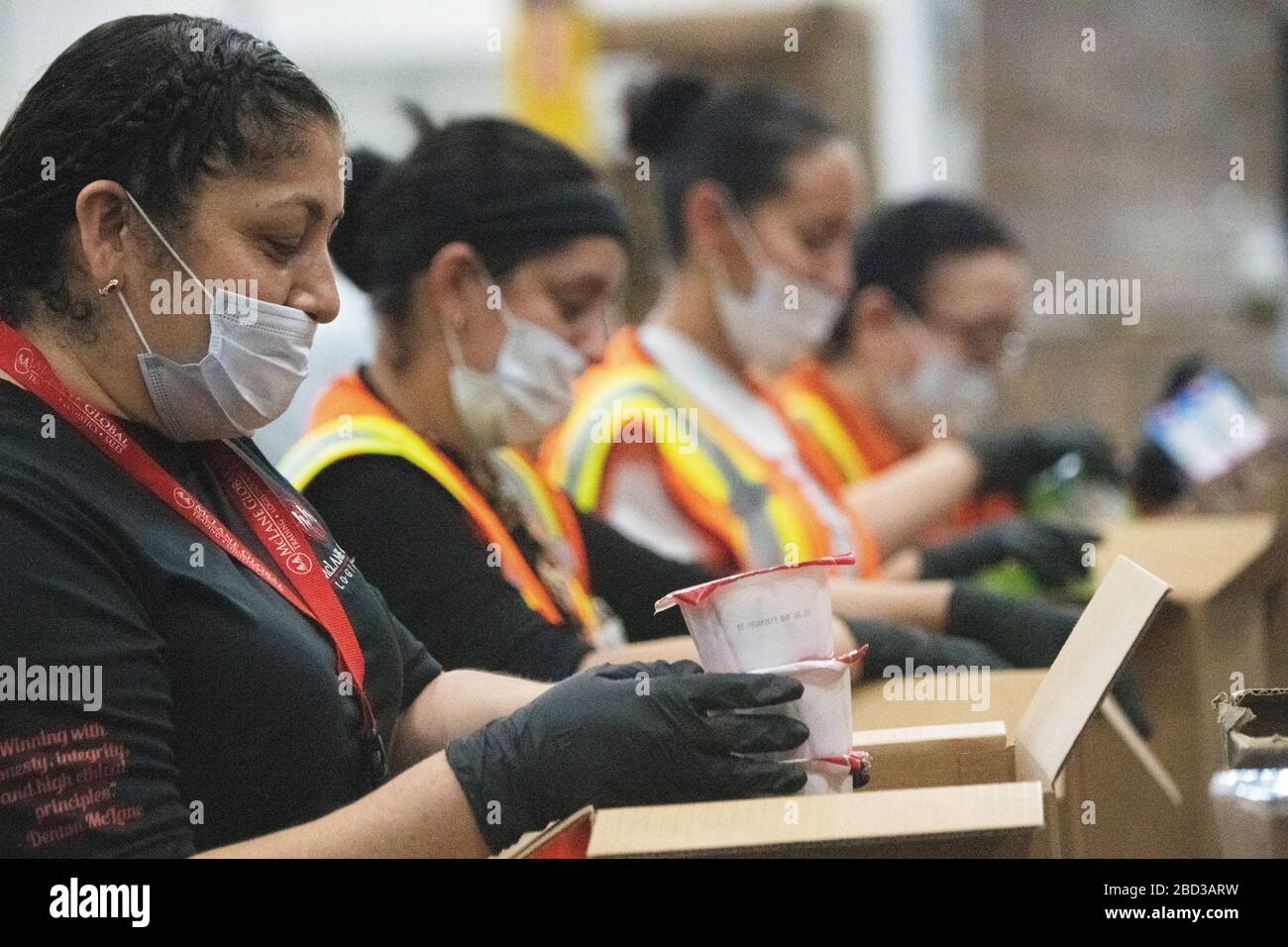 I dipendenti di McLane Global confezionare scatole di cibo per gli studenti nelle scuole rurali chiuso a causa della pandemia COVID-19 26 marzo 2020 a Houston, Texas. McLane Global in collaborazione con il Dipartimento dell'Agricoltura degli Stati Uniti, PepsiCo e Baylor Collaborative stanno fornendo quasi 1,000,000 pasti alla settimana agli studenti che ne hanno bisogno. Foto Stock