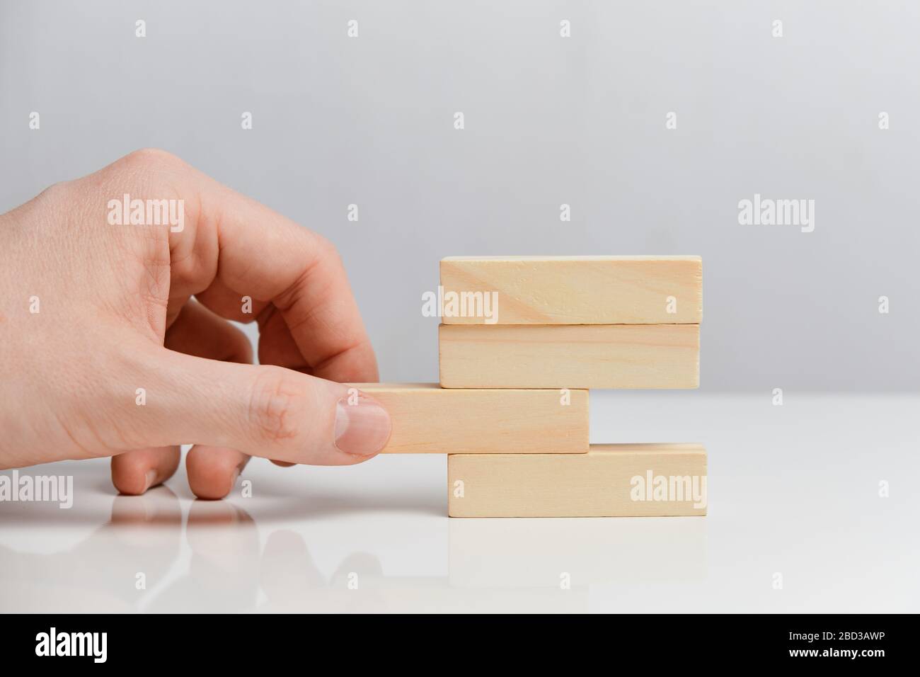 Concetto di azioni sbagliate nel business. La mano tiene blocchi di legno su uno sfondo bianco. Primo piano. Foto Stock